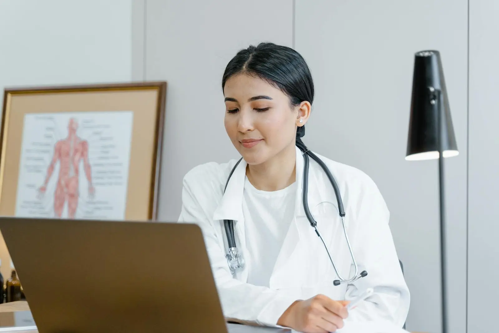 A doctor looking down at a screen in front of her during a telehealth consultation
